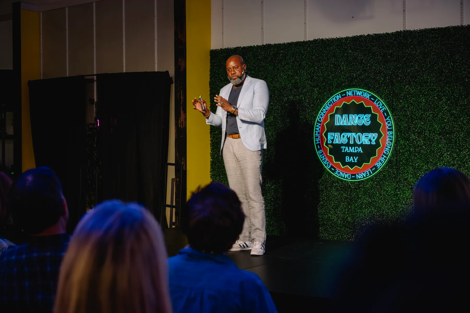 Hugo Maynard speaking on stage to a live audience
